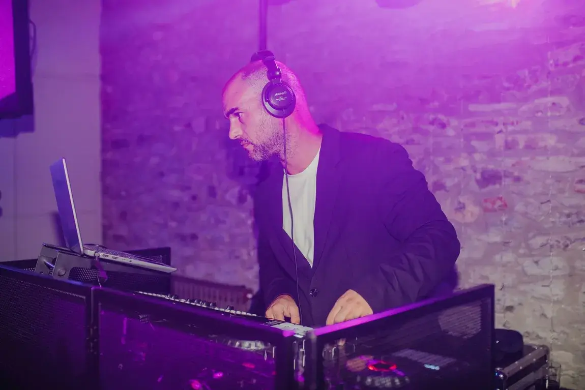 DJ mezclando música en la boda, rodeado de luces moradas y equipo tecnológico.